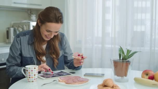 Femme utilisant un comprimé au petit déjeuner. Femme au foyer ayant brunch nutritionnel à la maison . — Video