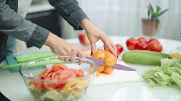 Woman cutting peppers with sharp knife in kitchen. Closeup hands slicing peppers — Stock Video