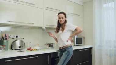 Modern mutfakta eğlenen mutlu kadın. Güler yüzlü kız lezzetli çorba hazırlanıyor.