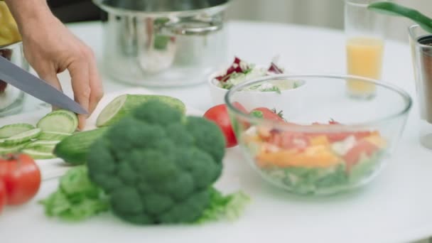 Primo piano uomo mani tagliando cetrioli per insalata fresca. Chef maschio fare insalata — Video Stock