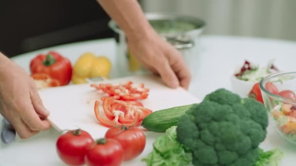 Close-up man handen zetten gesneden paprika's in de kookpot in slow motion. — Stockvideo