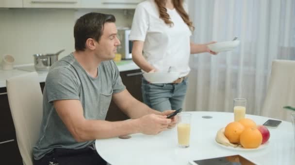 Pareja feliz bebiendo jugo de naranja durante el desayuno saludable en la sala de estar . — Vídeos de Stock