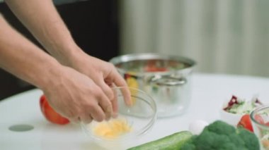 Closeup adam elleri tencereye çırpılmış yumurta ekleyerek. Adam eller pişirme malzemeleri