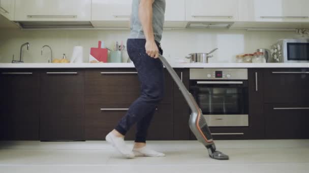 Hombre feliz limpieza piso con aspiradora en la cocina en cámara lenta . — Vídeo de stock