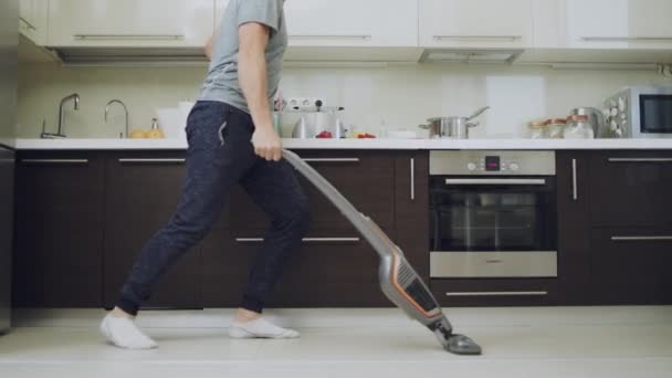 Happy man having fun with vacuum cleaner at kitchen. — Stock Video