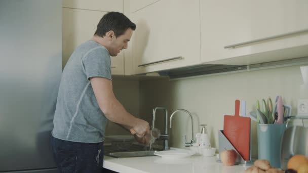 Alegre esposo haciendo tareas domésticas. persona sonriente lavado de vidrio — Vídeo de stock