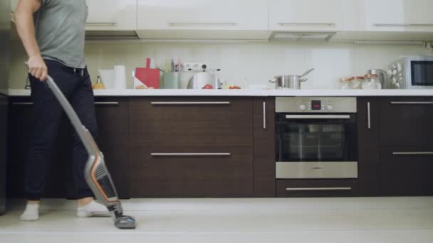 Homme attentionné nettoyage sol avec aspirateur à la cuisine moderne . — Video