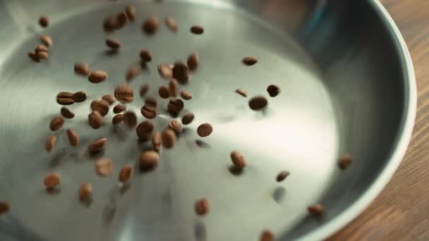 Rostade kaffebönor faller på metallskål yta i slow motion. — Stockvideo