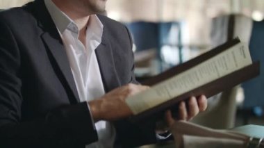 Restoranda yemek menüsünü seçen bir iş adamı. Şarap kartı arayan bir iş adamı.