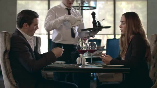 Счастливая пара встречается в ресторане. Официант обслуживает столик в ресторане — стоковое видео