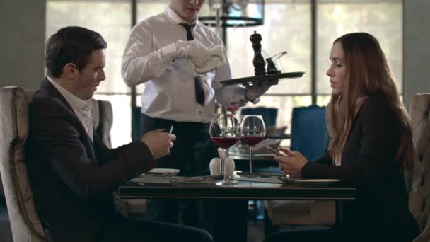 Feliz reunión de pareja en el restaurante. Mesero sirviendo mesa en el restaurante — Vídeos de Stock