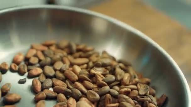 Grãos de cacau assar em panela em câmera lenta. Close up grãos de cacau jogando na panela — Vídeo de Stock