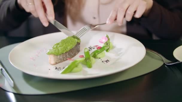 Mujer de negocios cortando pescado con cuchillo y tenedor en el restaurante — Vídeo de stock