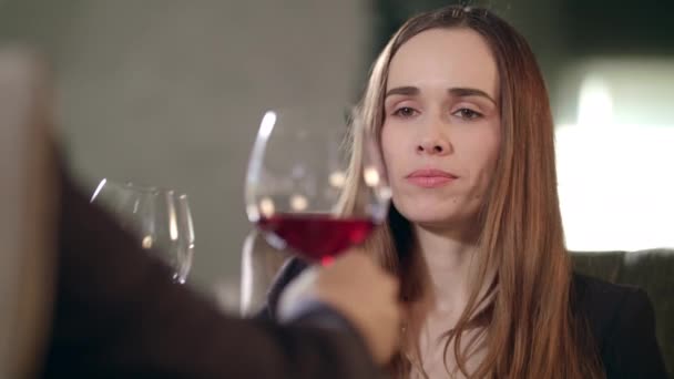 Женщина, звенящая красным бокалом вина с мужчиной в ресторане. Женщина пьет красное вино — стоковое видео