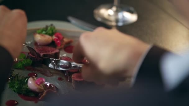 Manos masculinas cortando comida en el plato del restaurante. Hombre comiendo carne en restaurante — Vídeo de stock