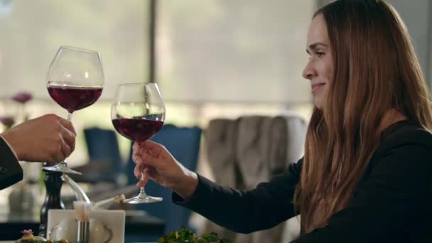 Привлекательная женщина, звенящая бокалом вина в ресторане. Женщина пьет красное вино — стоковое видео