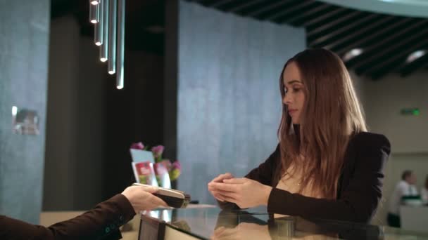 Zakenvrouw betaalt factuur met mobiele telefoon bij hotelreceptie — Stockvideo