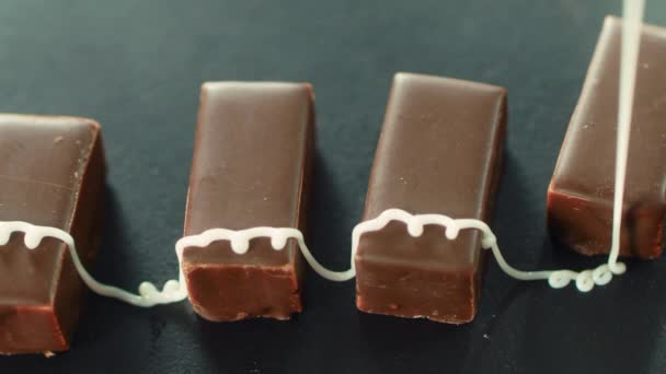 Xarope de açúcar derramando em doces de chocolate escuro. Bonbons com creme de gelo . — Vídeo de Stock