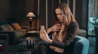 Kafedeki akıllı telefona bakan iş kadını yüz makyajını inceliyor.