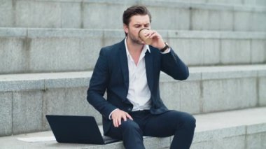 Sokakta dizüstü bilgisayarda daktilo yazan bir iş adamı. İçen adam kahveyi götürür.