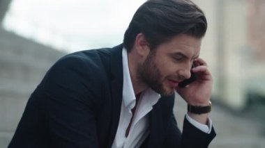 İş adamı sokakta cep telefonuyla konuşuyor. İşçi dışarıda zaferi kutluyor.