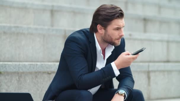 Confiado hombre de negocios grabación de mensajes de audio en el teléfono inteligente en la calle — Vídeo de stock