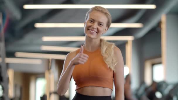 Donna fitness emotivo mostrando come in palestra. Sportiva in piedi nel club sportivo — Video Stock