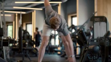 Yakışıklı, güçlü adam spor salonunda el sallıyor. Sporcu spor kulübünde ısınıyor.