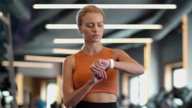 Spor salonundaki yorgun atlet kız sonuçları kontrol ediyor. Spor kulübünde duran sporcu kadın.