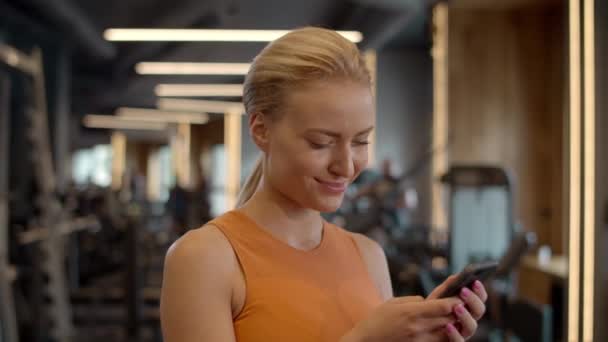 Romantisk idrottskvinna sms: ar på sportklubben. Idrottsflicka stående på gym — Stockvideo