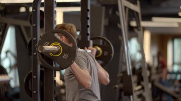 Ejercicio serio del culturista en el club del deporte. Deportista haciendo sentadillas en el gimnasio — Vídeos de Stock