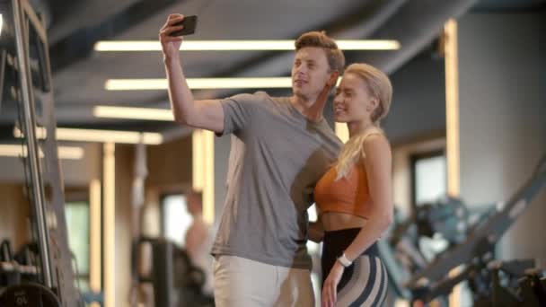Lächelndes Paar macht Selfie-Foto im Fitnessstudio. Fitter Mann beim Fotografieren im Sportverein — Stockvideo