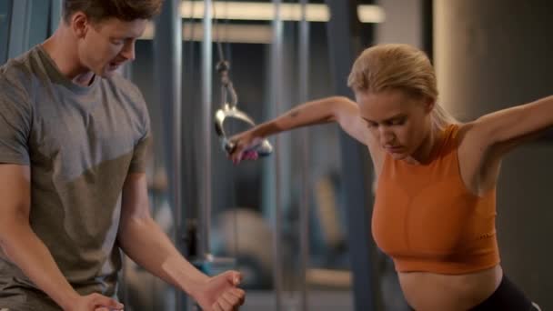 Entraînement sportif en couple dans un centre de fitness. Fit girl faire des boucles de bras à la salle de gym — Video