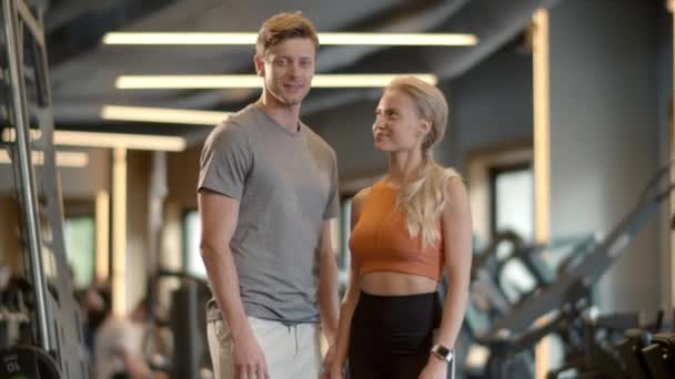 Ganadores pareja mostrando como signos en el club deportivo. Pareja disfrutando de los resultados en gimnasio — Vídeo de stock