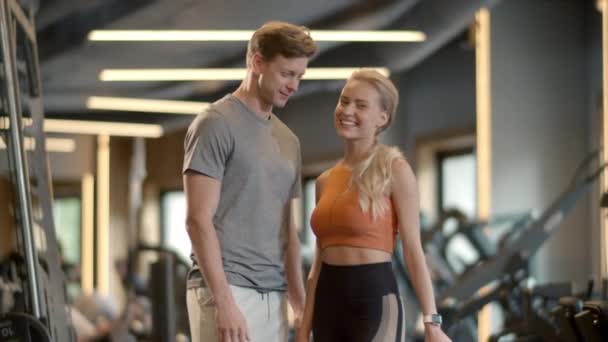 Aufgeregtes Paar genießt Erfolge im Sportverein. Fit Mädchen zeigt wie Zeichen im Fitnessstudio — Stockvideo