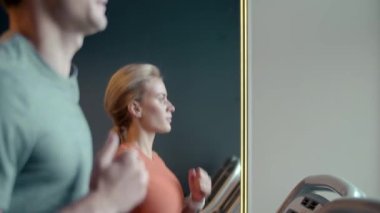 Spor kulübünde kardiyo yapan sağlıklı bir kız. Spor salonunda koşan bir çift.
