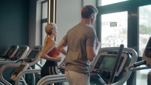 Pasująca para biegająca na bieżni na siłowni. Sportowa rodzina robi cardio w klubie sportowym — Wideo stockowe