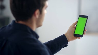 Close up male professional making video talk on green screen mobile phone.