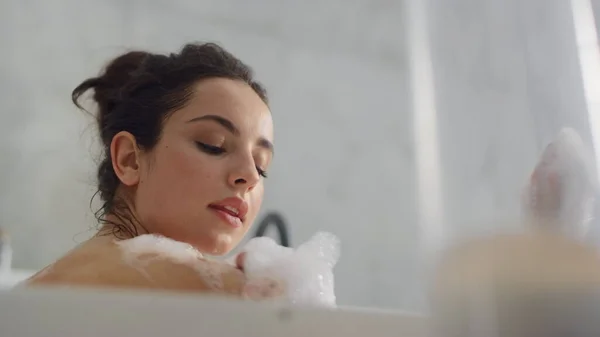 Primer plano sensual mujer soplando espuma en bañera cámara lenta . — Foto de Stock