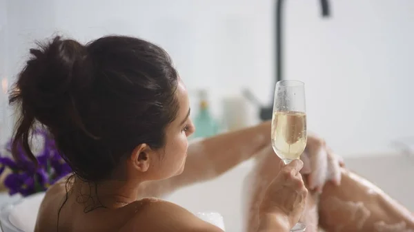 Sensuell kvinna som tvättar ben med skum i badkaret. Sexig tjej dricker champagne — Stockfoto