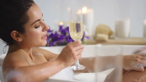 Sexy vrouw wassen benen met schuim in bad. Meisje dat champagne drinkt in bad — Stockfoto