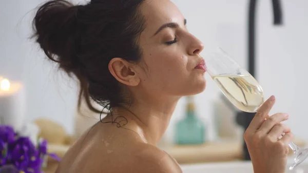 Avslappnad kvinna dricker champagne i badkaret. Sexig tjej kopplar av med ett glas vin. — Stockfoto