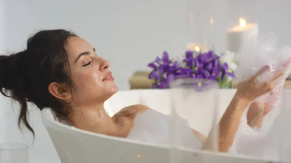 Closeup relaxed woman blowing foam at bath. Smiling woman having fun with foam. — Stock Photo, Image