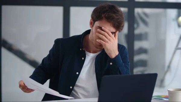Upset businessman finding mistakes in documents. Sad guy looking papers indoor