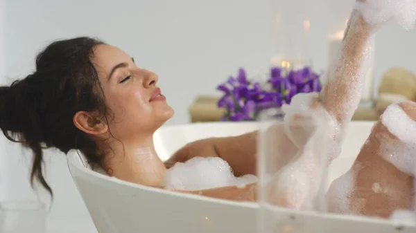 편안 한 여자는 거품 목욕으로 손을 씻는다. 욕조에서 쉬고 있는 섹시 한 소녀. — 스톡 사진