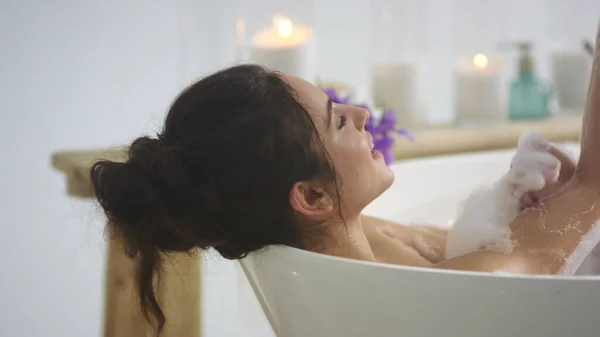 Close up relaxed woman touching skin with foam. Brunette woman relaxing bath — Stock Photo, Image