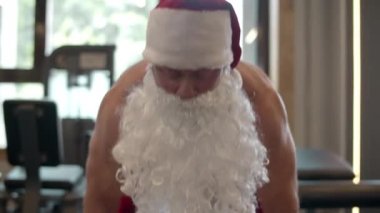 Odaklanmış Noel Baba spor kulübünde tekrarlar yapıyor. Noel Baba kostümlü fitness adamı.