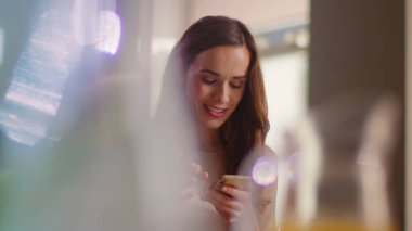 Smiling woman using smartphone at home. Lady holding mobile phone indoor