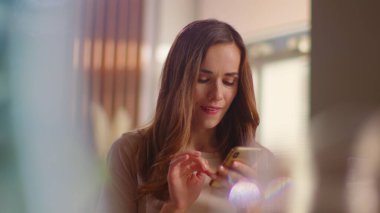 Woman typing on smartphone on kitchen. Lady texting message on mobile phone