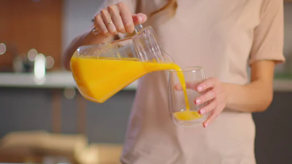 Woman pouring juice into the glass on kitchen. Lady drinking orange juice — Stock Photo, Image